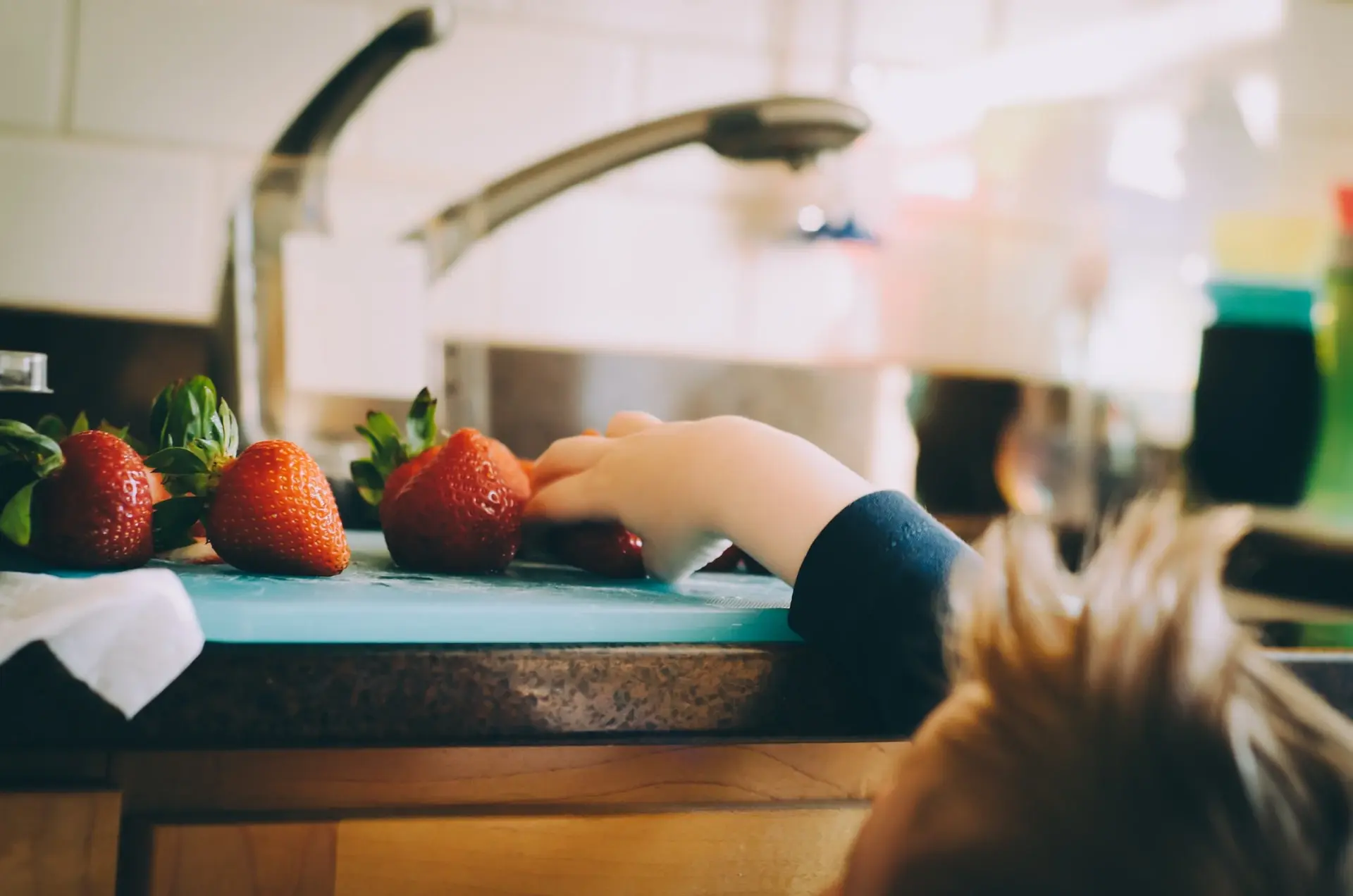 kid picking strawberries from the kitchen counter